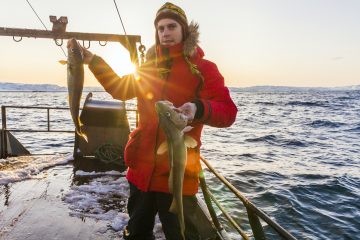 Young fisherman on the boat with two large fish